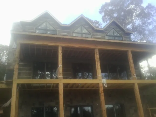 Dormers and porch framing on a large log home under construction — Roof Coating work by our crew in Elwood